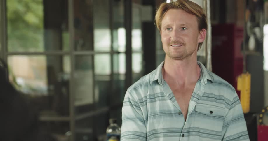 Man working on a workshop hands a towel to a friendly coworker