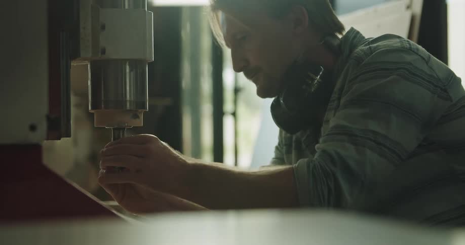 Man attaching a drill bit on a machine in a workshop