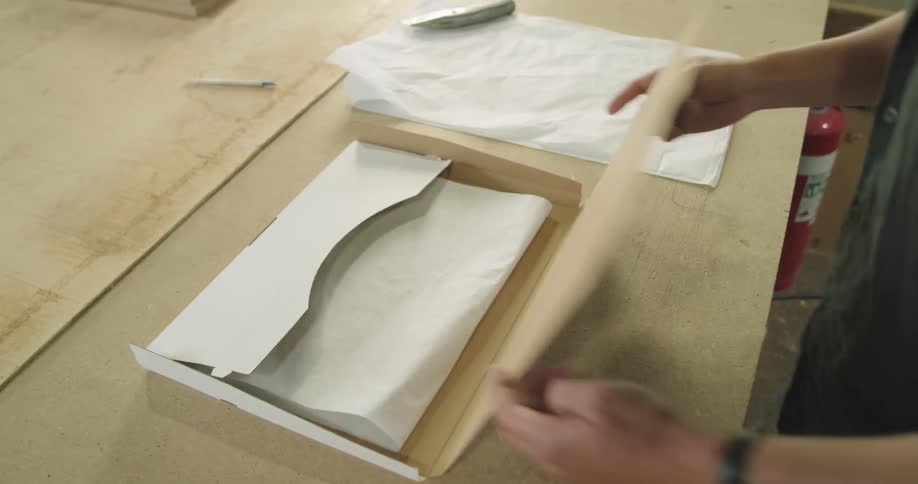A man places folded up tissue paper inside a white cardboard box