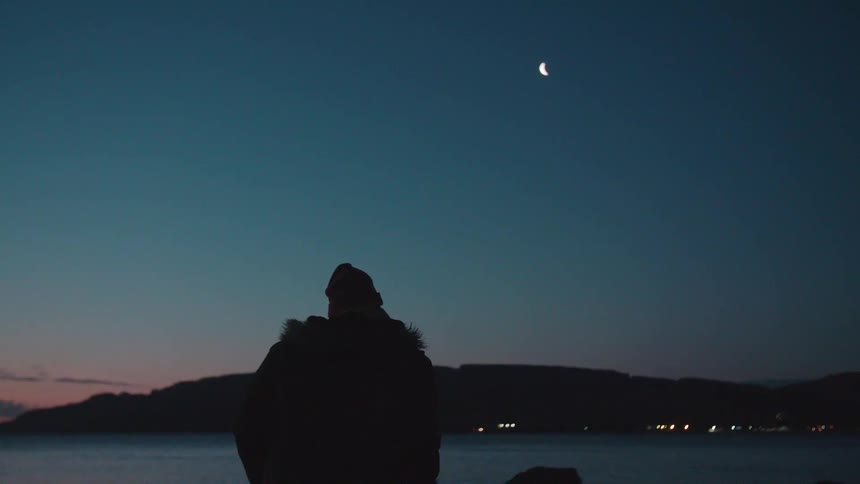 A man in a jacket looks out at water