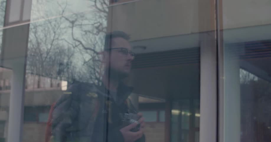 A man is holding a camera inside of a window