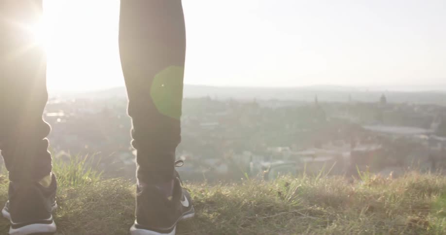 Close up of someone's calves and feet as they stand on the edge of a cliff