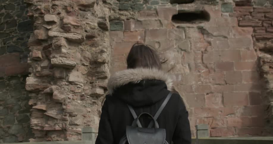 A woman is walking towards a brick building entering