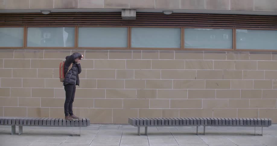 A person is taking a photo while standing on a bench