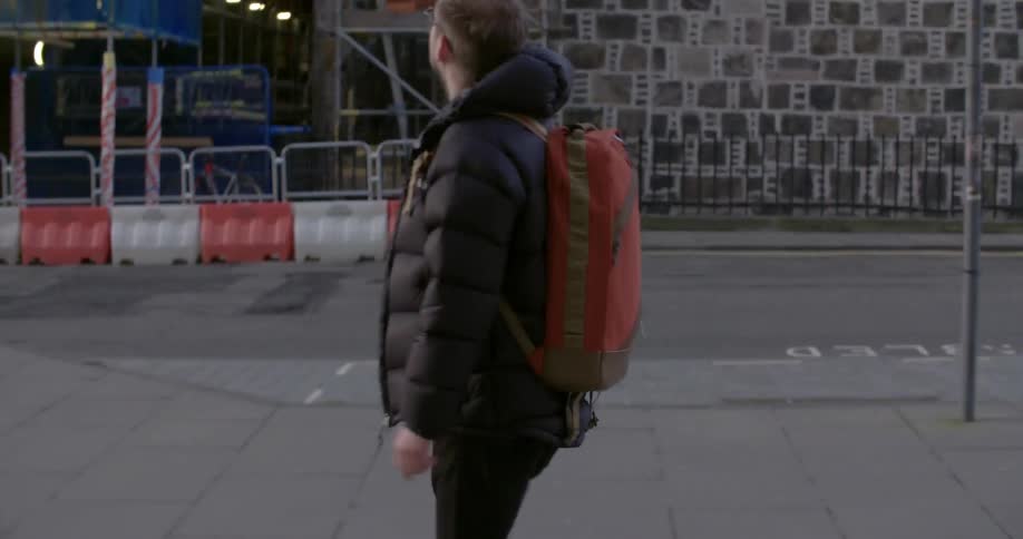 A man is walking along a street looking around