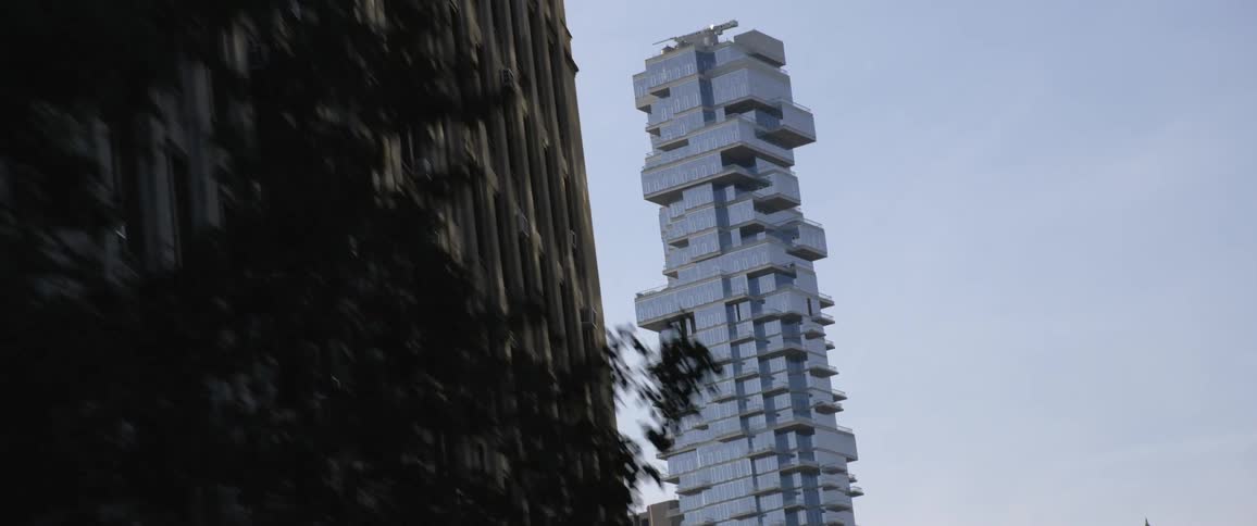 City with a white building and passing trees and traffic lights while moving down a street