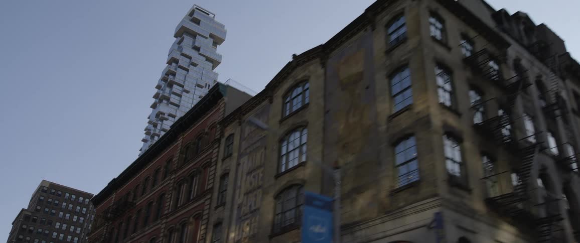 A stylish skyscraper looms over the small buildings along a road in a metropolis during the day