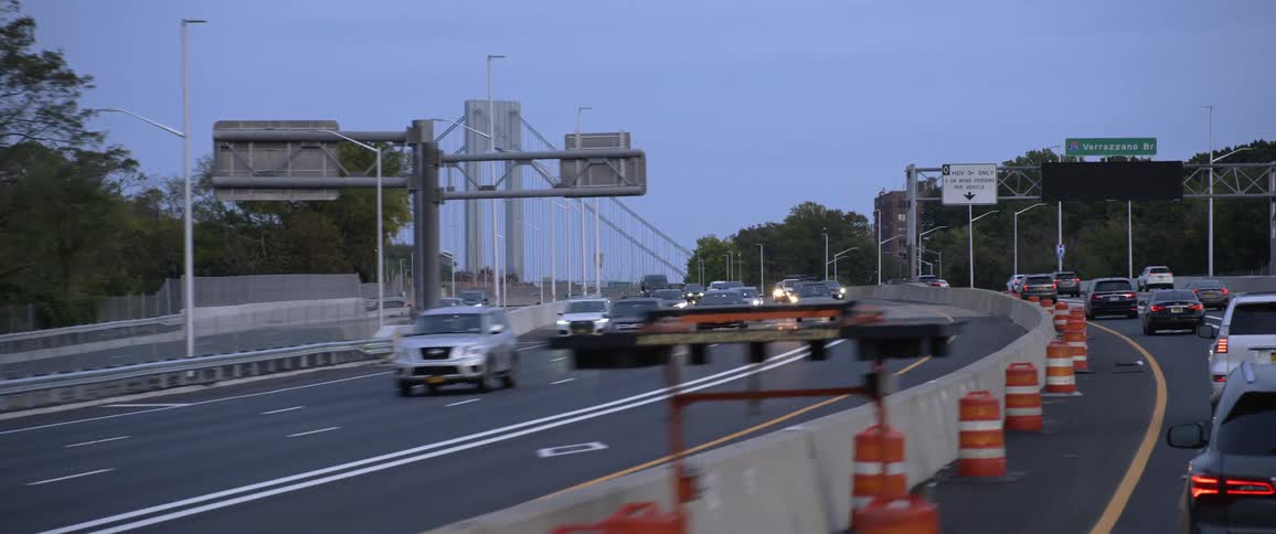 Vehicles traveling in a metro area with a suspension bridge in the distance