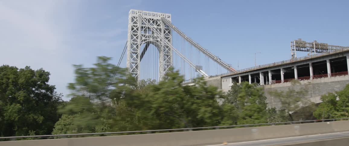 A suspension bridge amongst highways and ramps with a city in the background