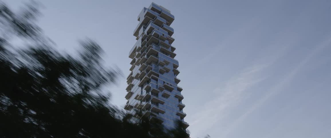 A tall skyscraper with many balconies jutting into the cloudy sky