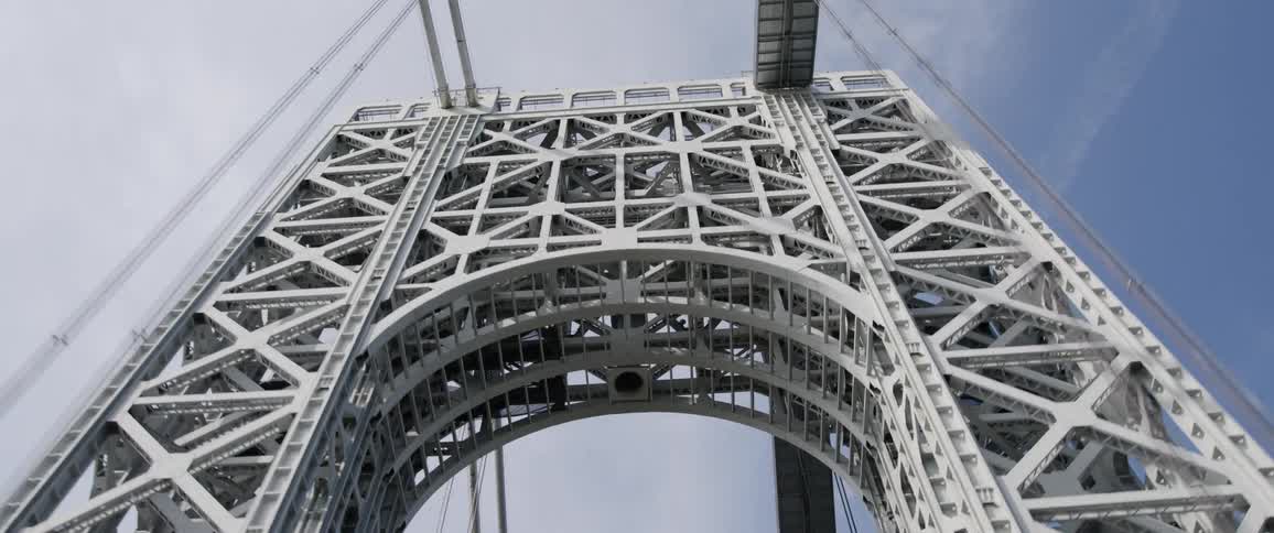 Point of view shot of a vehicle passing under the tower of a suspension bridge at day