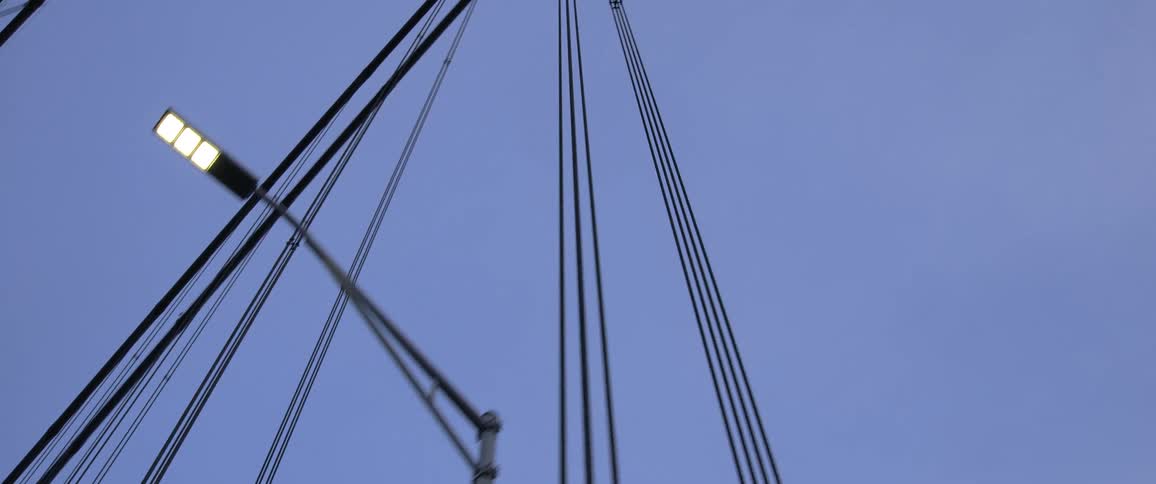 Moving across a bridge while looking up at the suspension cables and lights