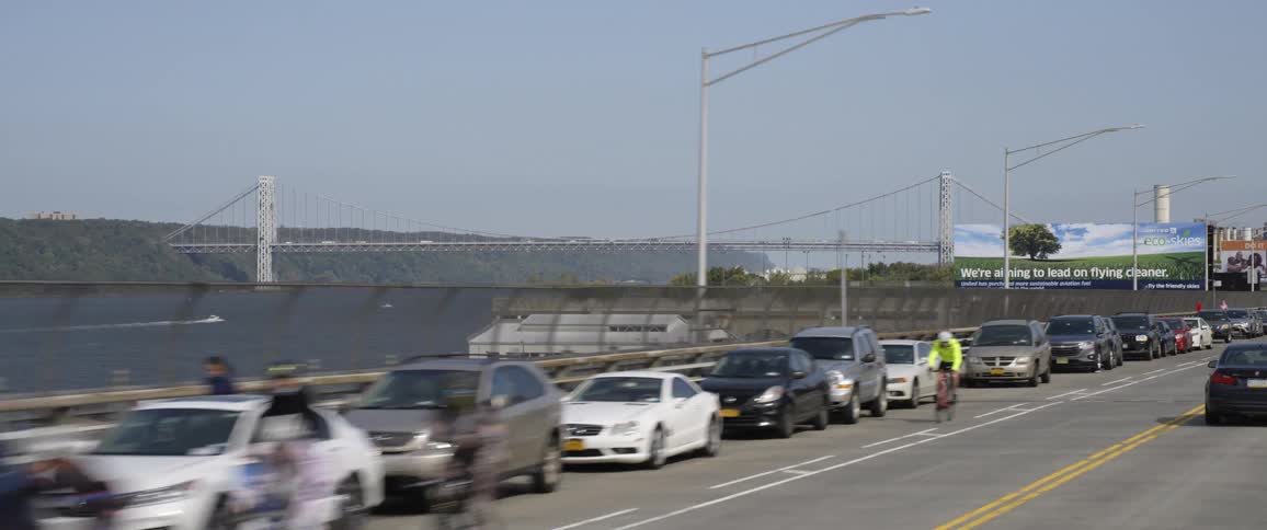 Group of cyclists driving bicycles on a road near a bridge over a river