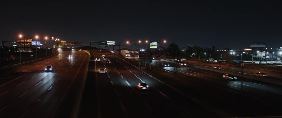 Traffic moves back and forth on a large freeway in a metropolis at night