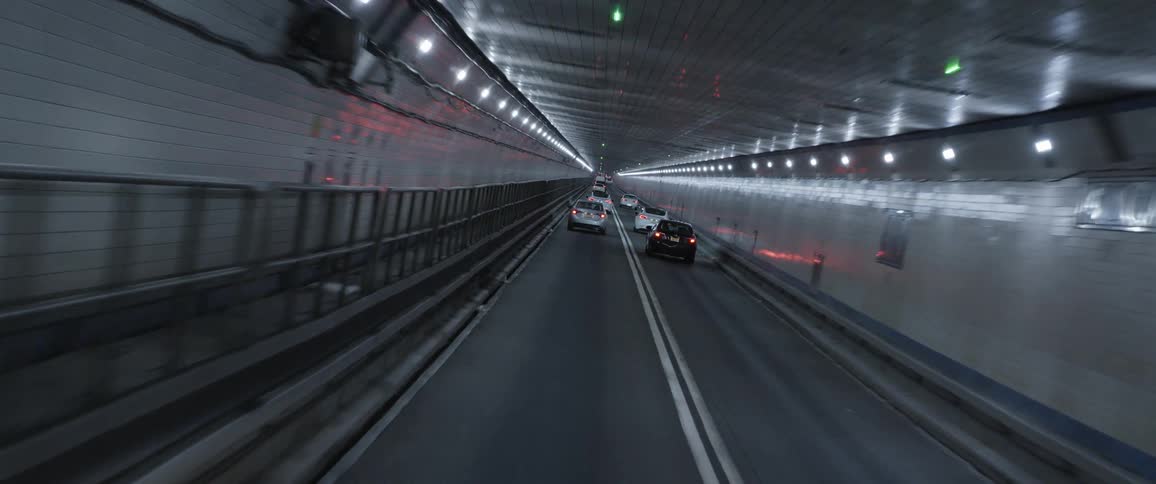 Twisting footage of vehicular traffic driving inside a tunnel