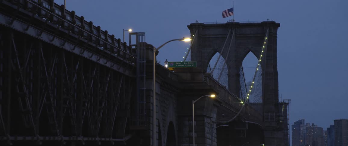 Brooklyn bridge tower with the american flag in the evening