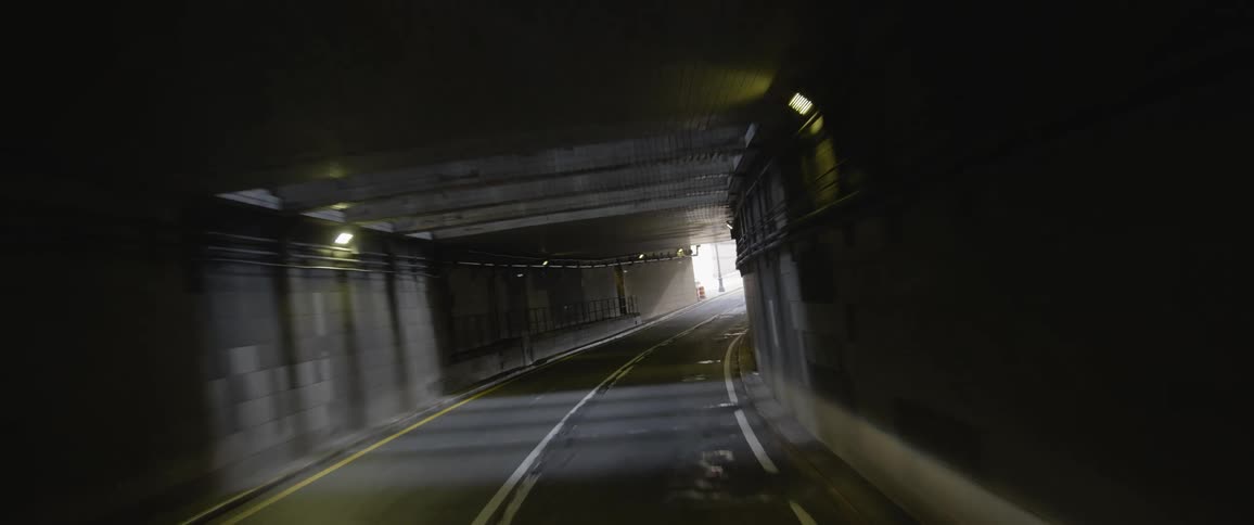 A road in a tunnel with lights leading outside to traffic