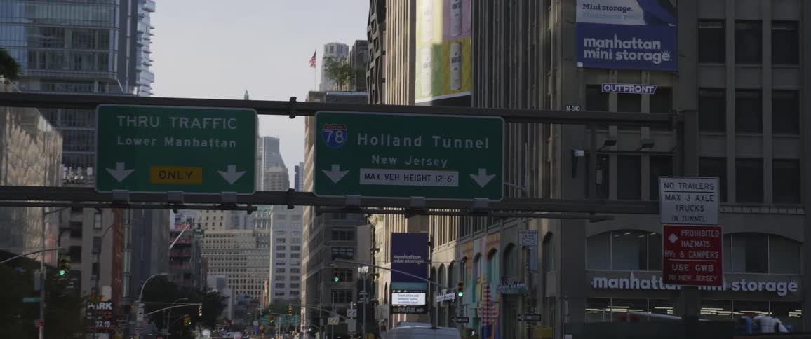 Cars driving on a busy city street surrounded by skyscrapers