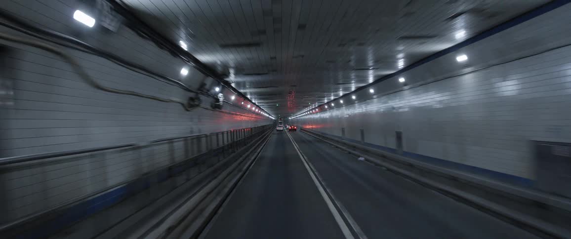 Traveling in a long white tunnel with vehicles in the distance