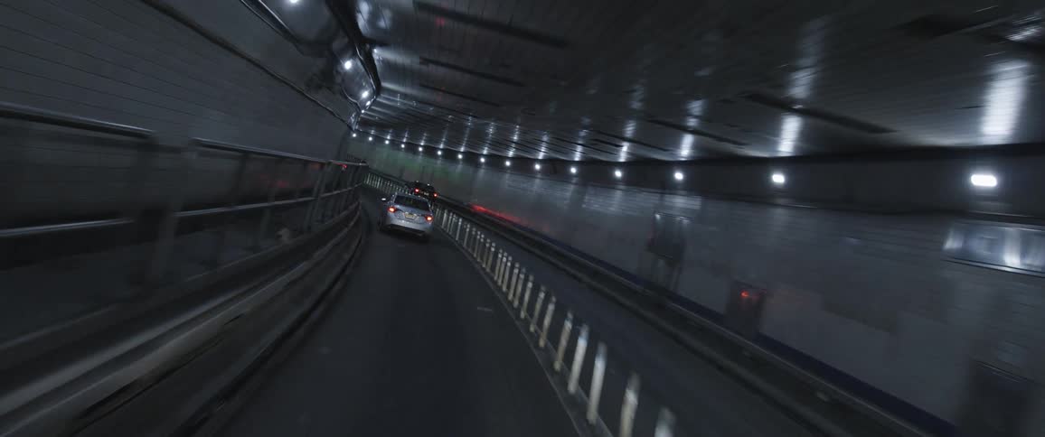 Interior of a tunnel with lights and guard rails with a car