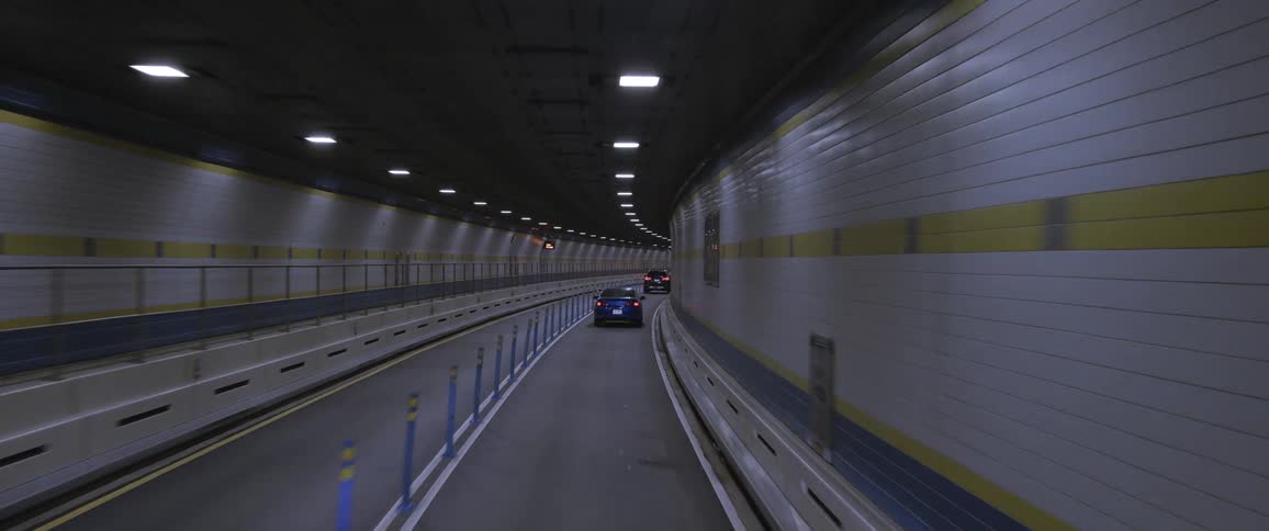 Traffic travels along a narrow road through a tunnel