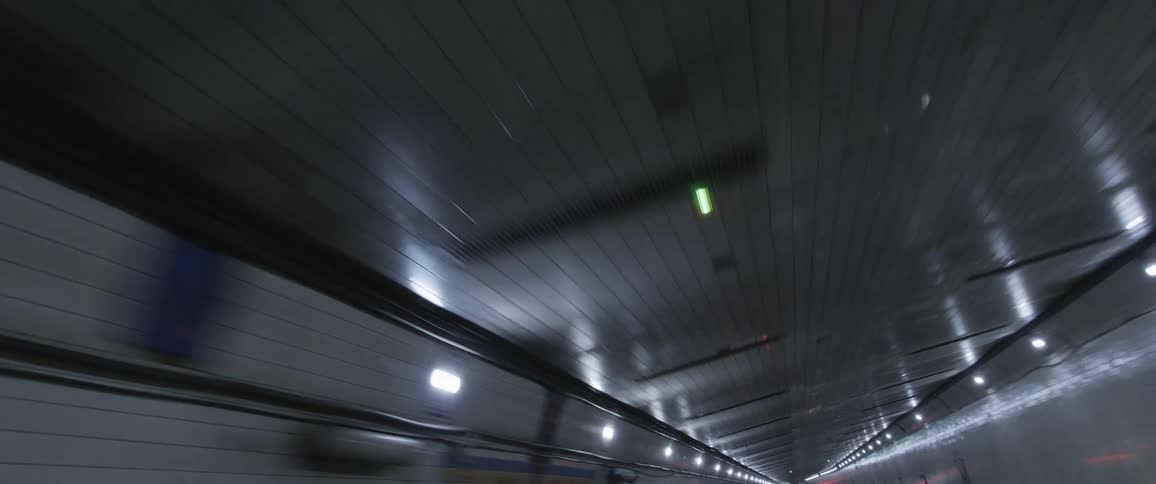 Twisting footage of lights reflecting on the ceiling over vehicular traffic inside a tunnel