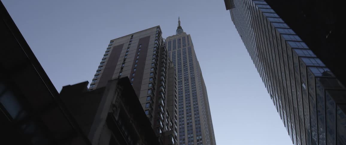 Tall buildings and skyscrapers line a road in a metropolis on a sunny day