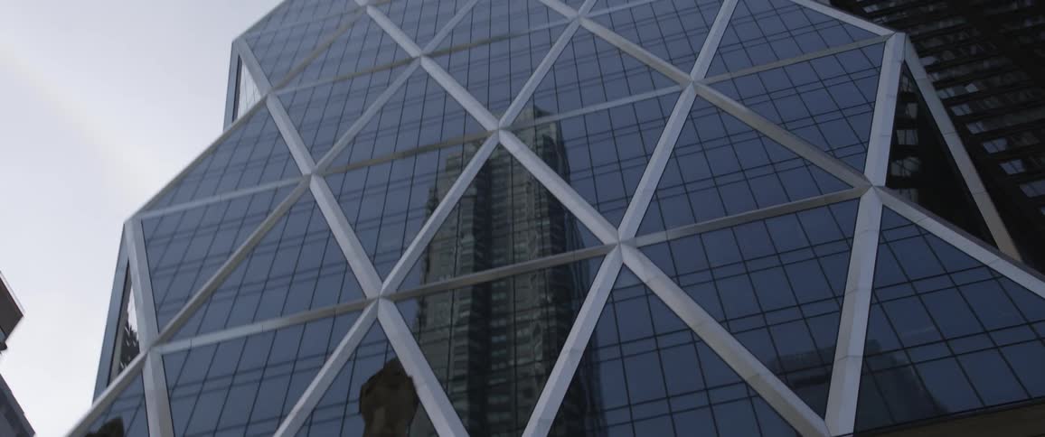 Buildings on a sunny day in a city with the reflection of other buildings in the glass windows