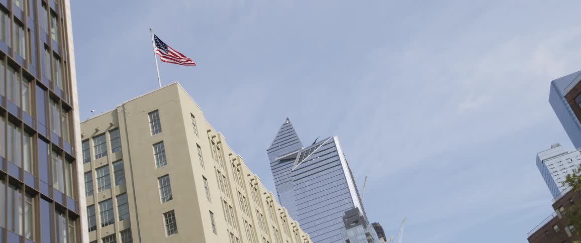 A steel building stone building with an amercian flag are against a blue sky