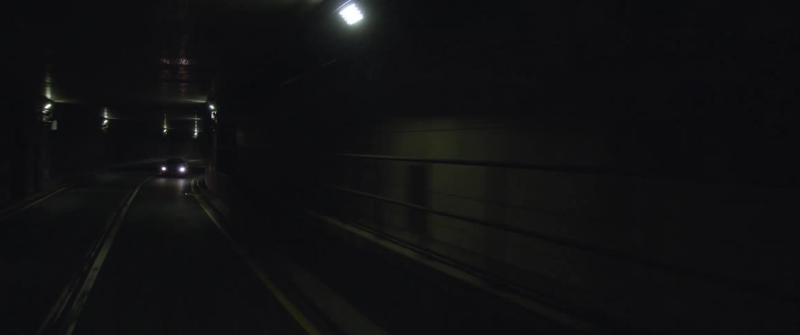 Cars drive on two lanes in dark tunnel