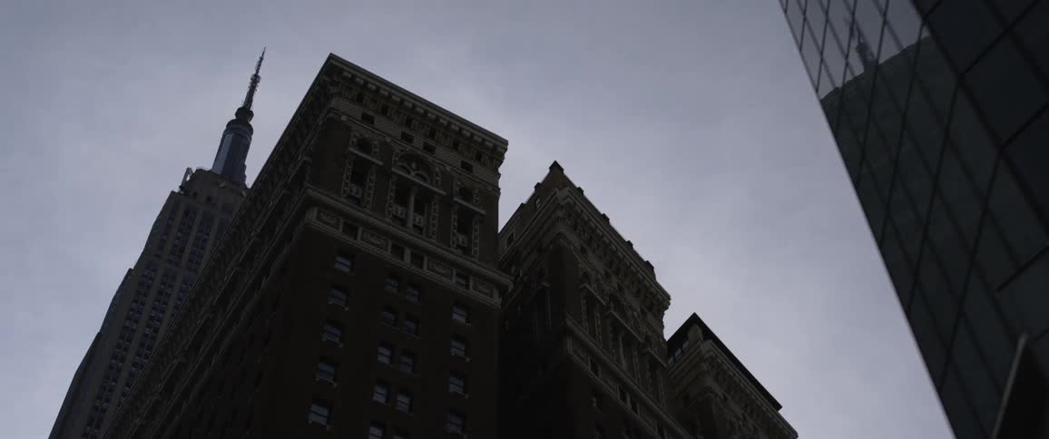 A helicopter flies over a city just above tall skyscrapers