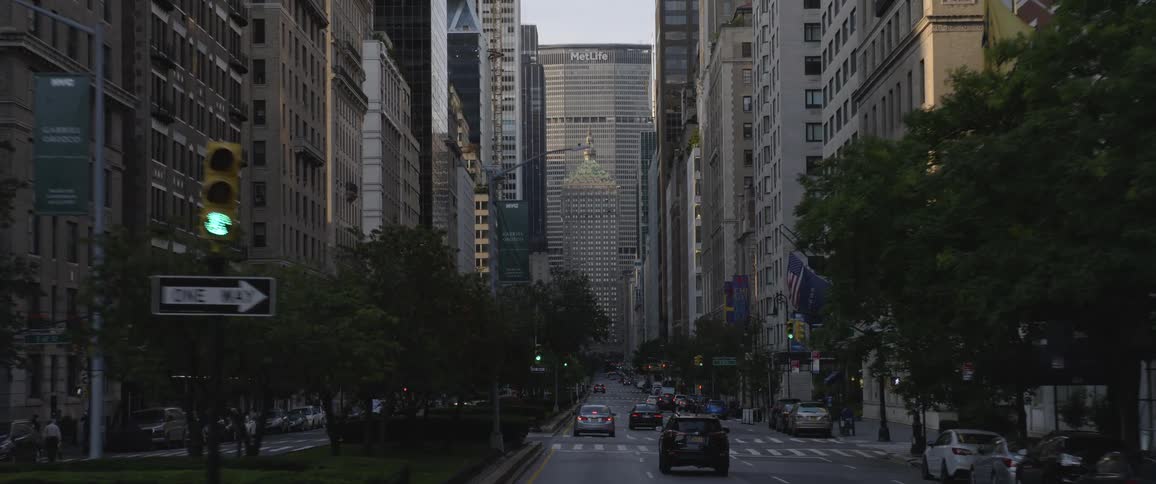 Cars drive down the road in a downtown urban environment with skyscrapers