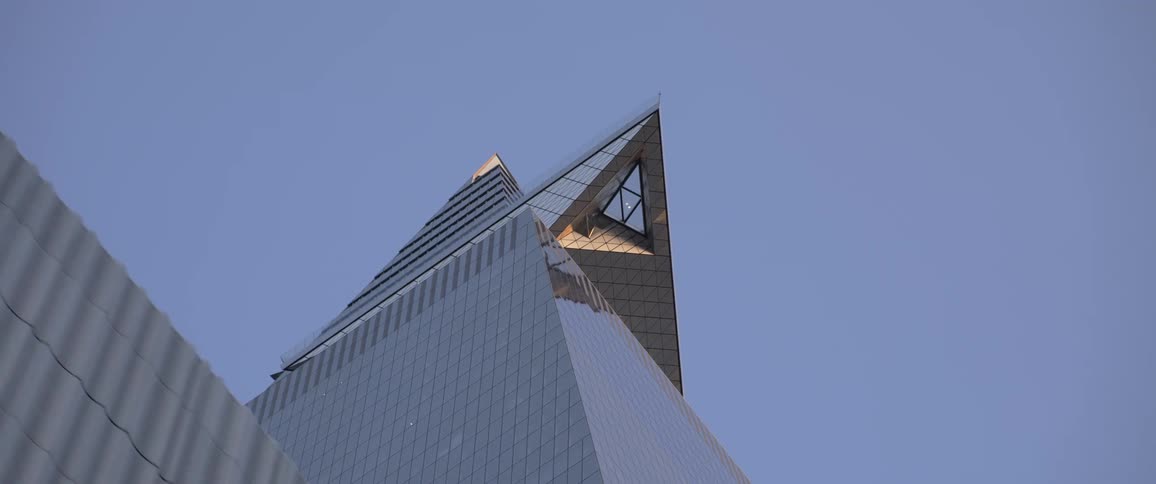 A steel building with windows and a pointed canopy at the top against a blue sky