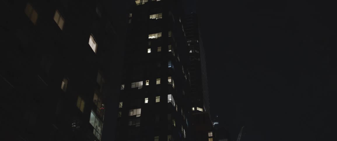 Buildings in a city at night with windows illuminated from the interior