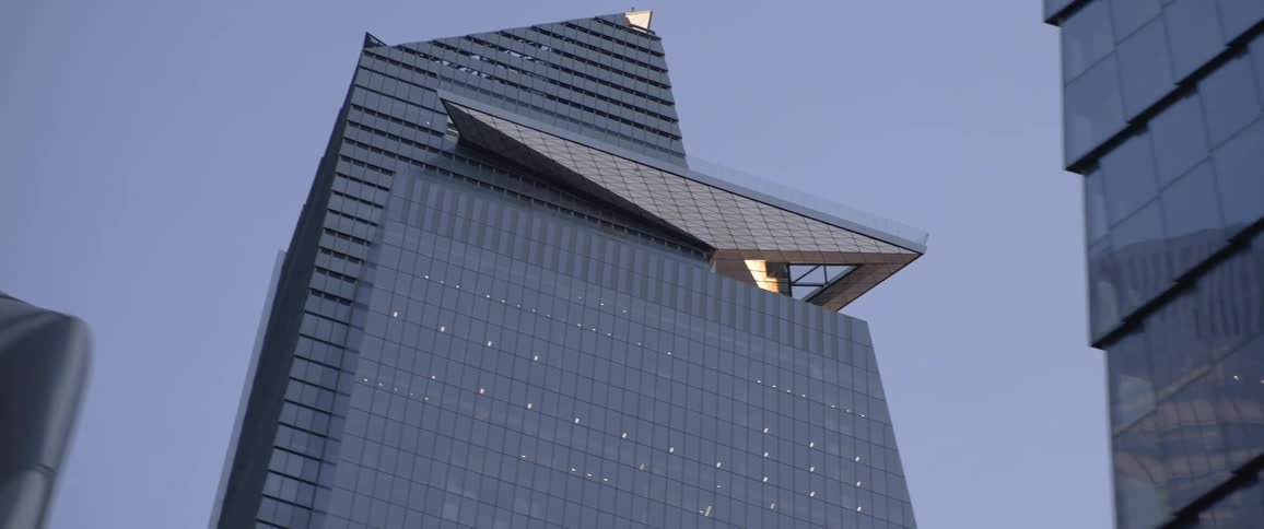 Glass surface skyscrapers reflect gray tinted sky