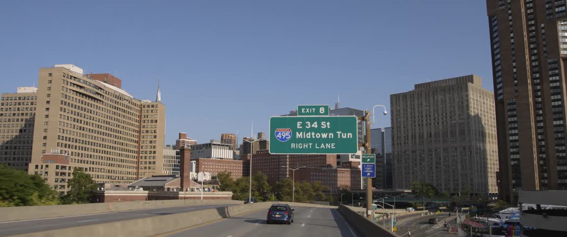Cars traveling on a city street with buildings in the distance