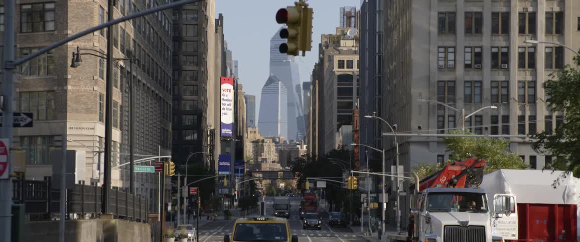 A downtown street with cars trucks traffic and street signs surrounded by buildings in daylight