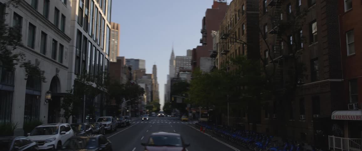 A wide intersection lined with tall buildings in a metropolis during the day