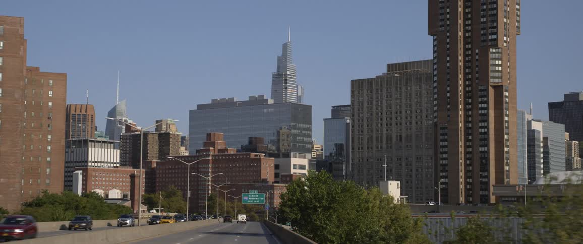 Tall skyscrapers in new york city skyline filmed from a highway at day time