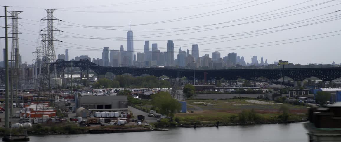 Distant skyscrapers loom over the industrial section of a metropolis on a cloudy day