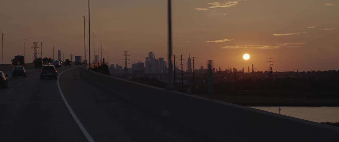 Vehicle driving across a bridge heading towards a city skyline