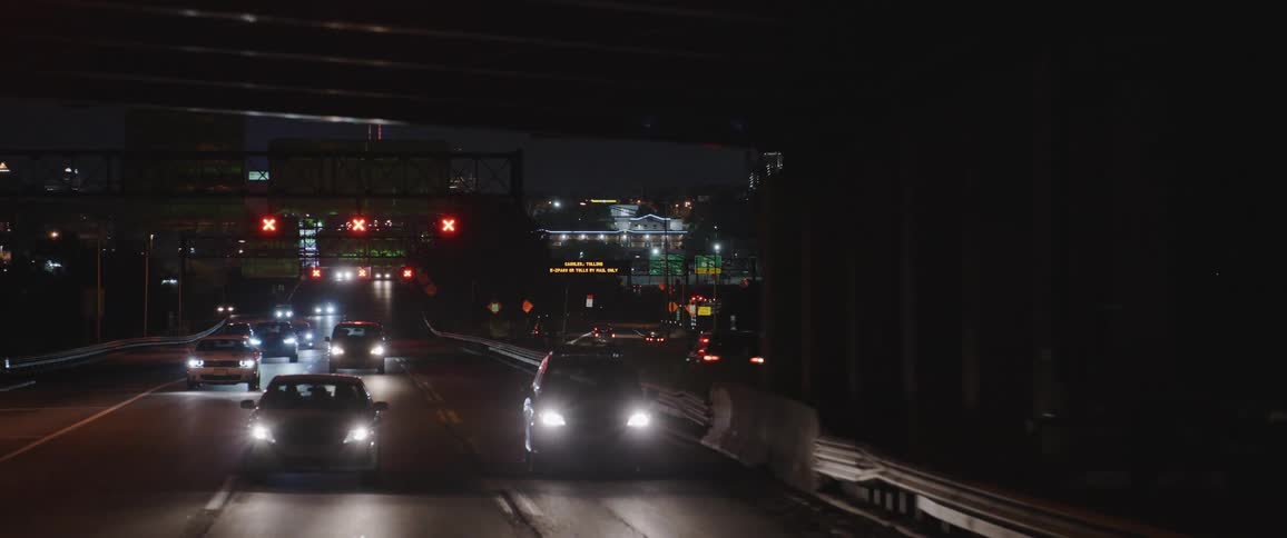 Traffic travels along a large freeway through a metropolis at night
