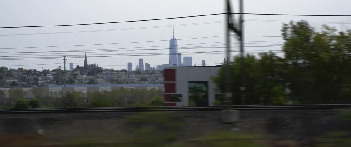 A city skyline with a skyscraper and tall buildings is along a river front