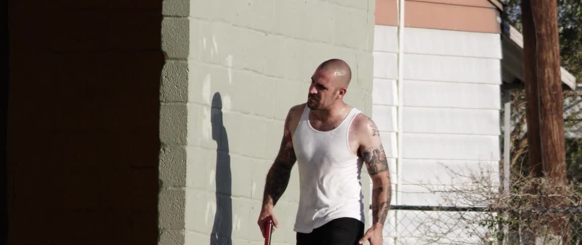 Tattooed man carries a handgun in a city