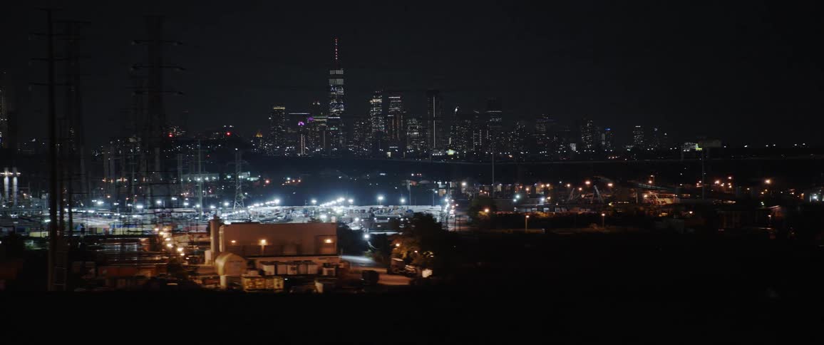 A sports stadium and skyline view from a road with traffic at night