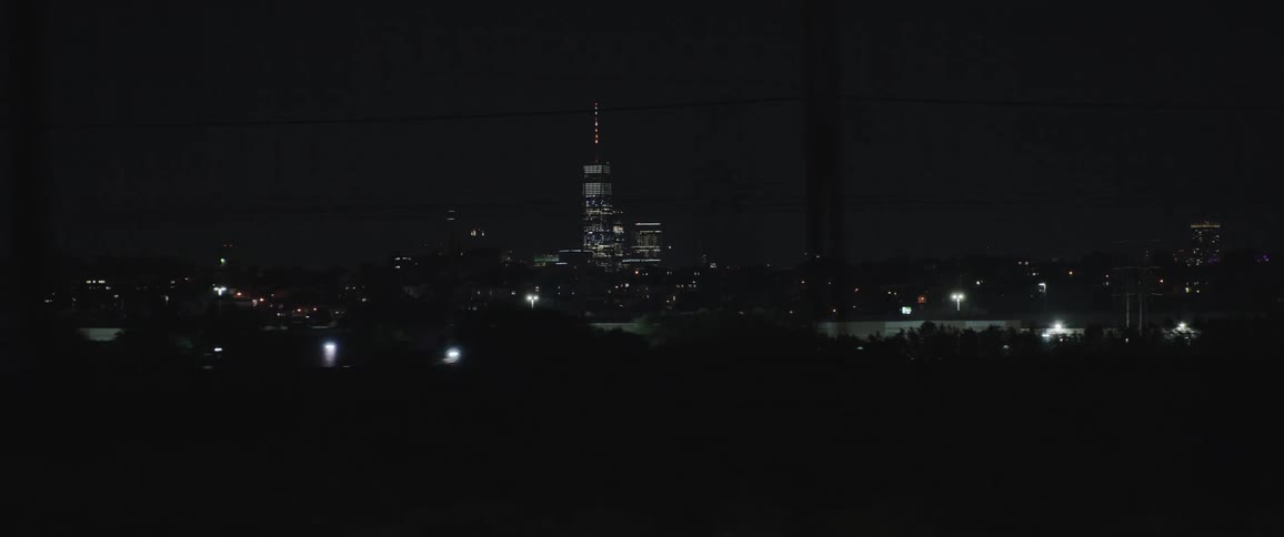 Driving at night in a city with a skyscraper in the distance