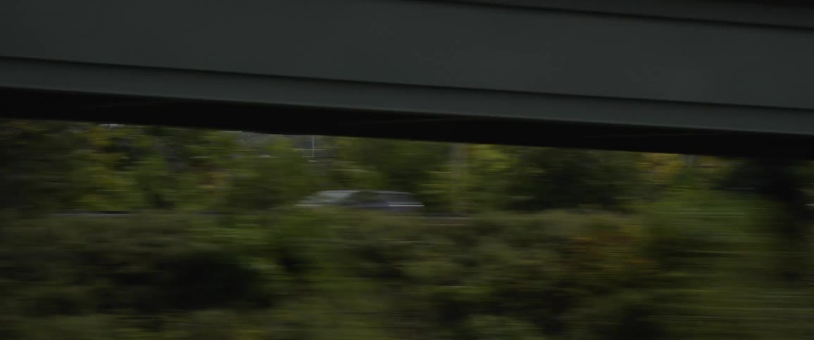 Cars traveling in an urban area with city skyscrapers in the distance