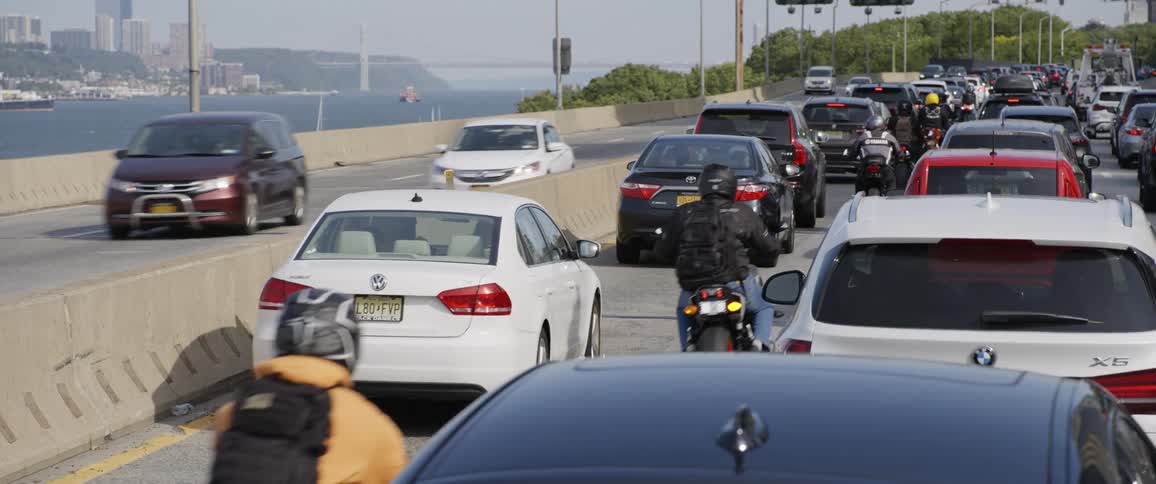 Motorcycles lane splitting between rows of slow traffic on a highway