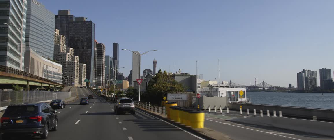 Cars driving down a city street with office buildings and the waterfront