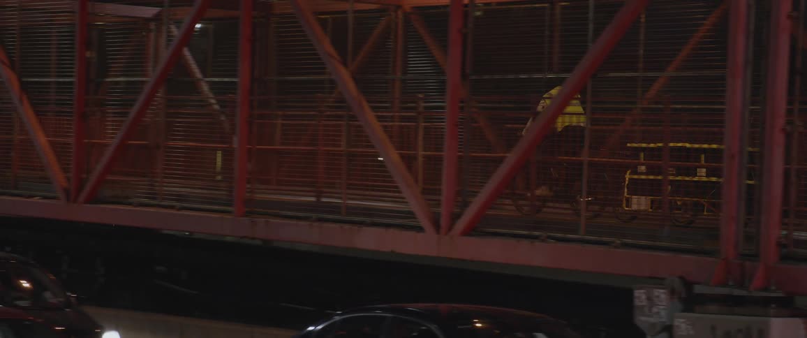 A person pulls containers across a bridge on their bike at night